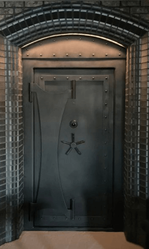 A large grey vault door inside of a gothic archway.