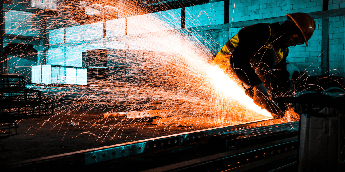 A metal worker making cuts on a metal door.