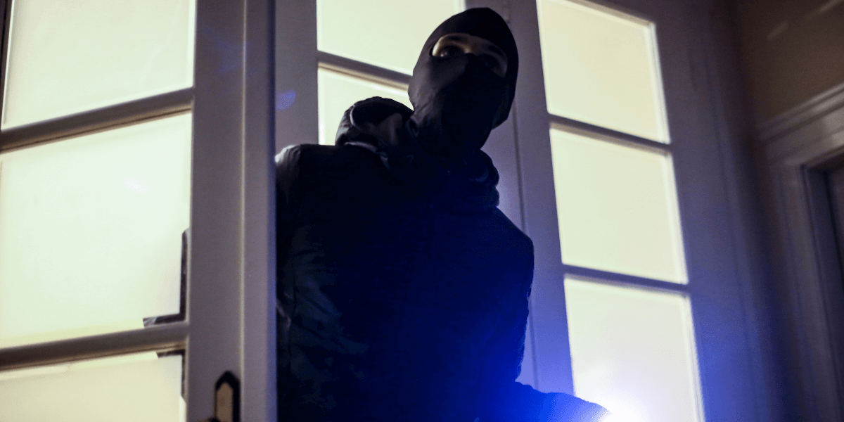 A burglar entering a home through a door.